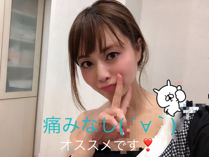 肩こり注射を受けた吉沢明歩さんの画像です。右肩がはだけていて、右手で左頬の前付近でピースサインをしています。